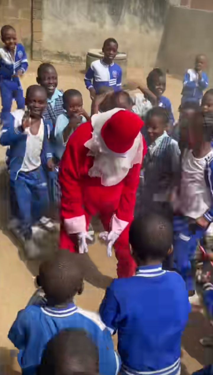 Nigerian lady dressed as Father Christmas entertaining school children